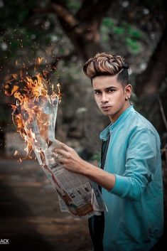 a young man holding a newspaper with fire coming out of it