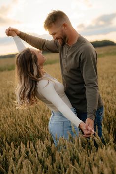 a man and woman holding hands in a wheat field