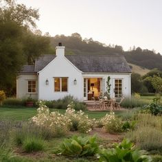 a small white house sitting on top of a lush green field