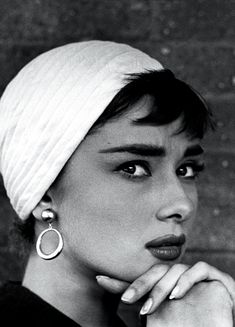 a black and white photo of a woman wearing a turban with her hand on her chin