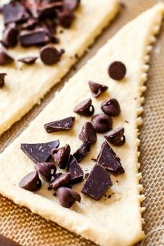 two pieces of chocolate sitting on top of a piece of bread with some chips scattered around it