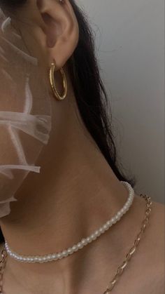 a close up of a woman wearing a necklace with pearls and gold chains on her neck