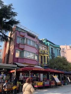 a woman is walking down the street in front of some colorful buildings with shops on each side