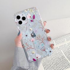 a woman is holding up her phone case with flowers on the front and back cover