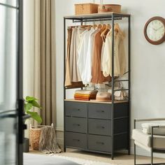 an open closet with clothes hanging on the rack and a clock mounted to the wall