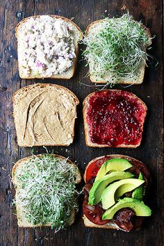 four slices of bread with different toppings on them sitting on top of a wooden table