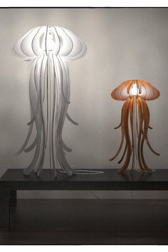 two lamps that are sitting on top of a table next to each other in front of a white wall