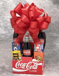 a coca - cola gift basket filled with assorted sodas and chocolates, wrapped in red ribbon