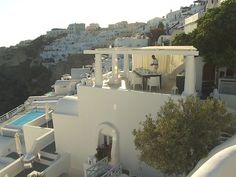 an aerial view of a white building with pool in the foreground and mountains in the background