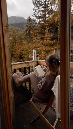 a woman sitting in a chair on top of a wooden deck next to a window