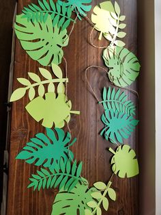 paper cut out of leaves on a wooden surface with string and twine attached to them