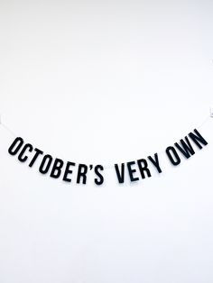 a black and white banner that says october's very own hanging from a string