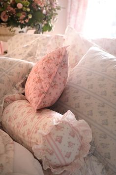 pillows piled on top of each other on a bed with pink flowers in the background