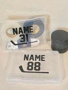 the name and number of hockey stickers are displayed in plastic cases on a table