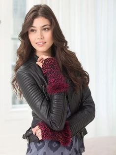a woman wearing a black leather jacket and red knitted mittens is posing for the camera