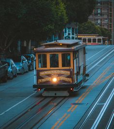 a trolley car is going down the street at night time in san francisco, california