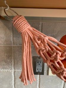 an orange hanging from a hook on a tiled wall next to a light switch and electrical outlet