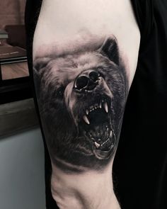 a man's arm with a bear tattoo on it and his mouth is open