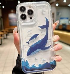 a woman holding up a phone case with a blue whale on the front and bottom