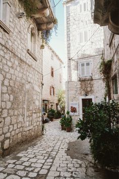 an alley way with stone buildings and potted plants