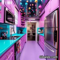 this kitchen has purple cabinets and blue counter tops with colorful lights hanging from the ceiling