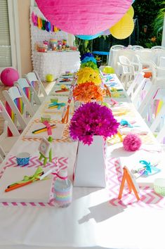 the table is set up with colorful flowers and paper napkins on top of it