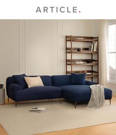 a blue couch sitting on top of a wooden floor next to a book shelf filled with books