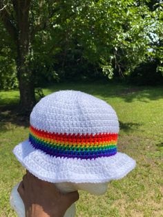 a person wearing a white crocheted hat with a rainbow stripe on the brim