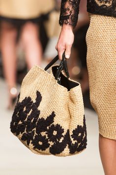 a woman carrying a black and white handbag on the runway at a fashion show