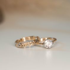 two gold wedding rings sitting on top of a table