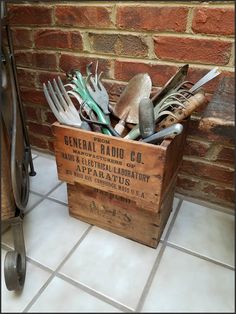 a wooden box filled with lots of different types of utensils in front of a brick wall