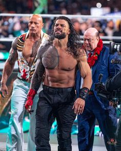 the wrestler is surrounded by photographers as he walks through the ring