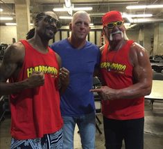 three men in red shirts and blue shorts posing for the camera with one man wearing sunglasses