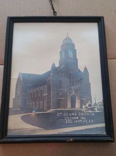 an old photo hanging on the wall in front of a building with a clock tower