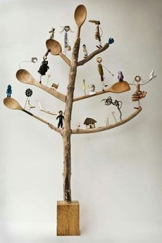a tree made out of spoons with people standing on it and holding utensils