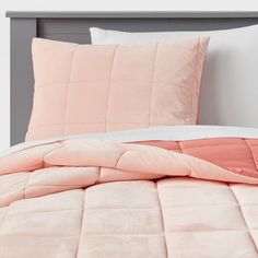 a bed with pink comforter and pillows on it