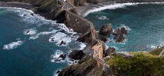 an aerial view of the ocean and coastline with people walking on it, along with some cliffs