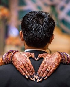 the back of a man's hands with henna tattoos on his arm and chest