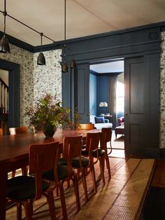 a dining room table with chairs and a vase on top of it in front of a doorway