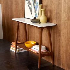 a table with a vase on it next to a wooden paneled wall and shelf