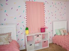 two twin beds with pink sheets and pillows in a girls'bedroom decorated with sprinkles