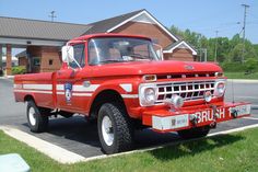 an old red truck is parked in the parking lot