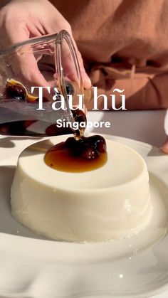 a person pouring sauce on top of a dessert