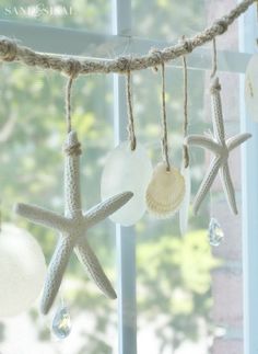 starfish and seashells are hanging from a rope in front of a window