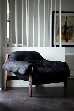 a black chair sitting on top of a hard wood floor next to a white wall