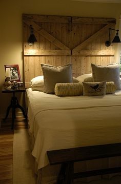 a large bed with pillows and lamps on the headboard in a room that has wood paneling