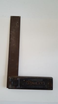 an old fashioned metal ruler with the word stanley on it's side and a black handle