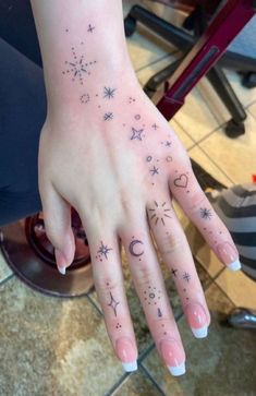 a woman's hand with stars and moon tattoos on it