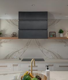 there is a bowl of fruit on the kitchen counter top next to an oven hood