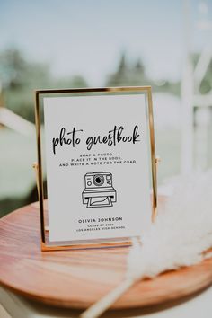 a photo guest book sitting on top of a wooden table next to a white feather